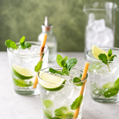Refreshing lime mojito cocktails with fresh mint, crushed ice, and lime wedges in glass cups